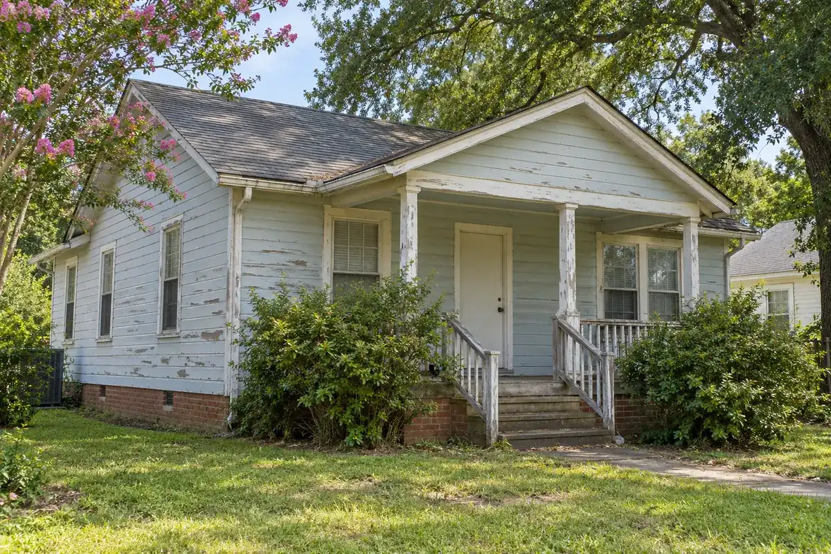 A house with peeling paint and worn roof shingles that needs repairs